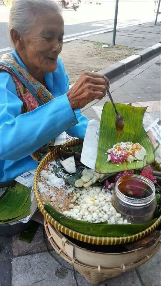 A vendor preparing a snack on a banana leaf at a street stall
