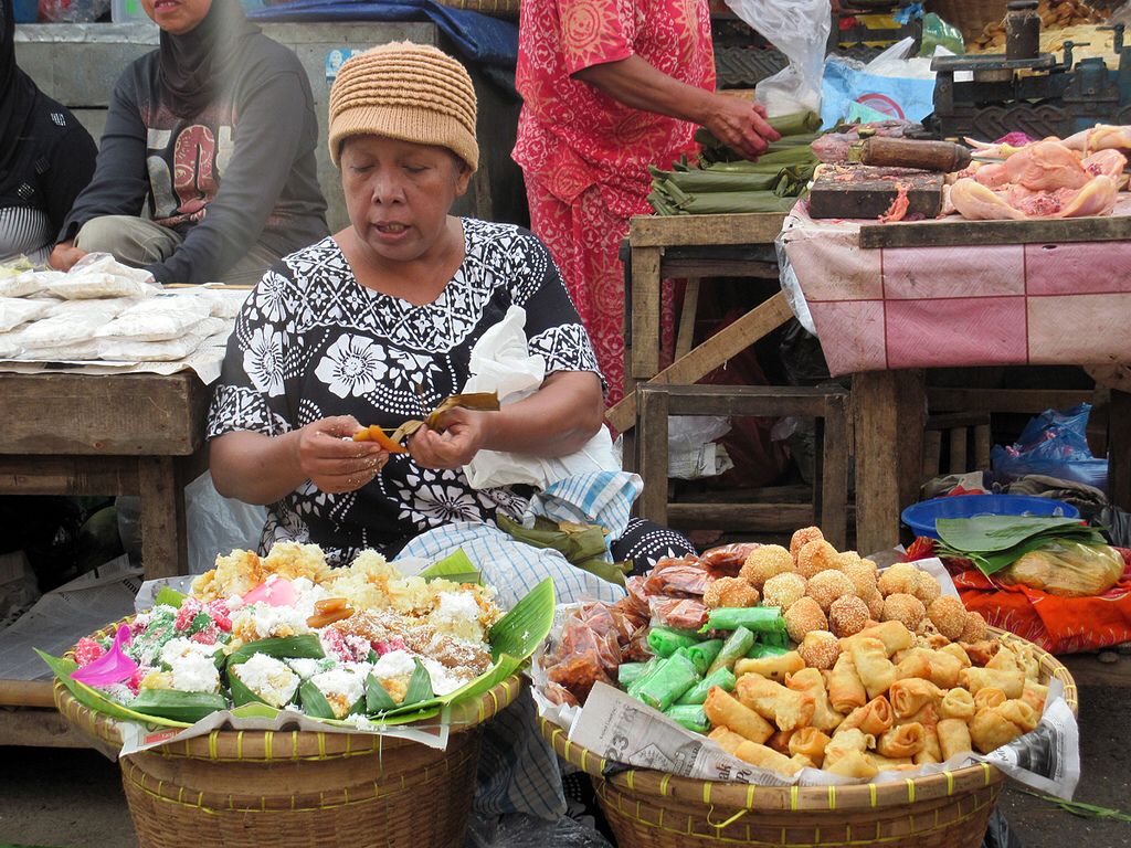 A market vendor arranging baskets of traditional snacks